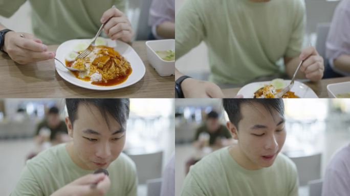 一个年轻人和朋友在自助餐厅吃饭，用叉子和勺子吃着一口酥脆的猪肉饭，上面撒着美味的酱汁。