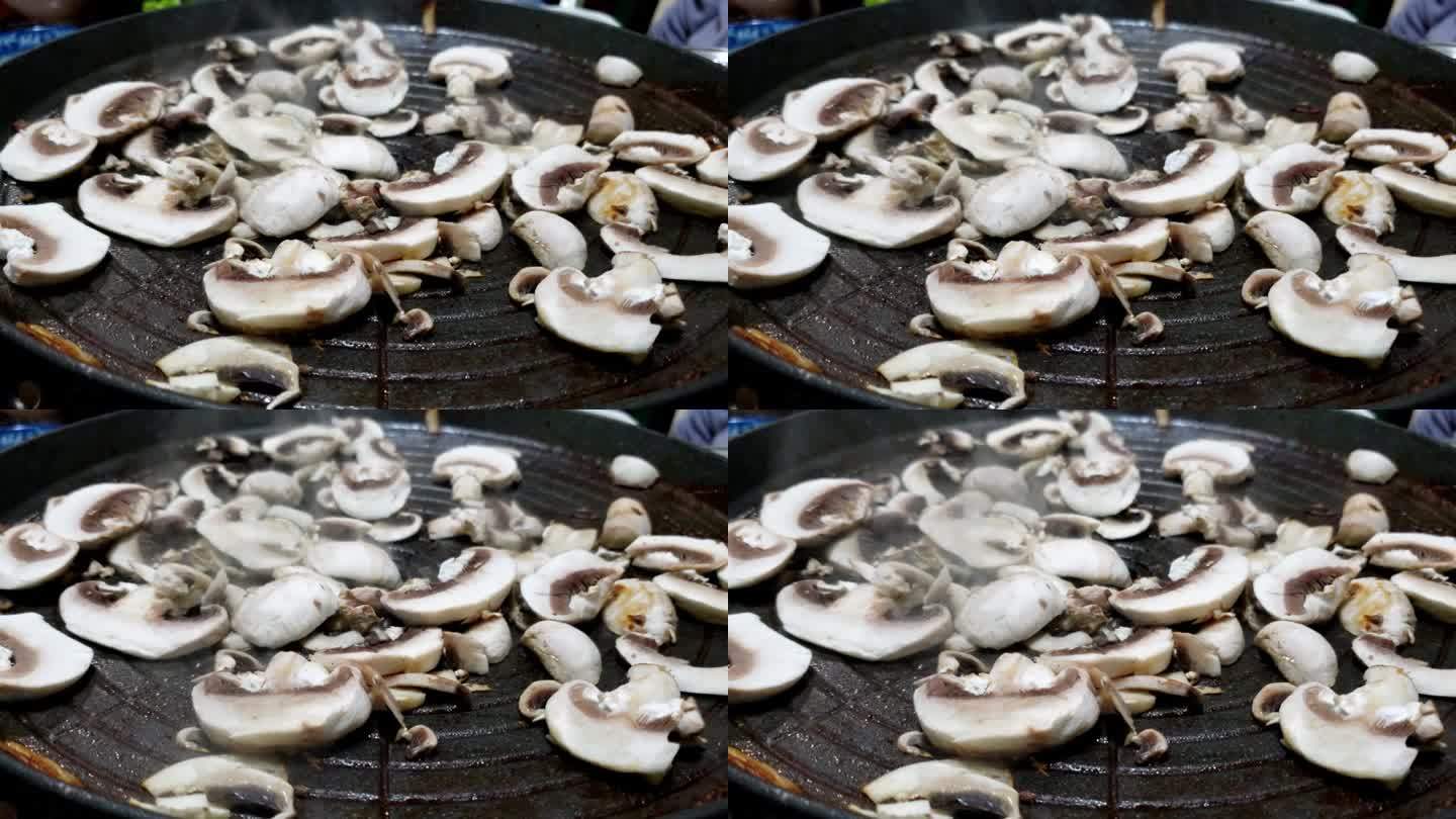 切成薄片的鲜蘑菇在热盘子上滋滋作响