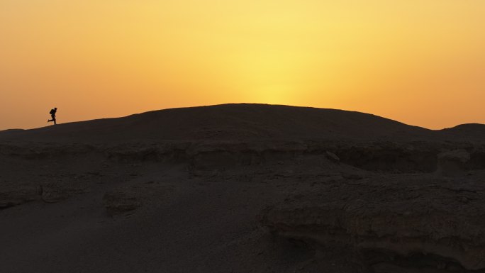 新疆哈密大海道雅丹风蚀地貌夕阳下奔跑的人