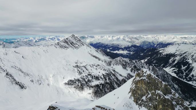美丽的电影航拍雪山高山冰川高峰。远处的山谷和陡峭的积雪覆盖着山脉。无人机在峰顶横飞，惊人的景观景色观