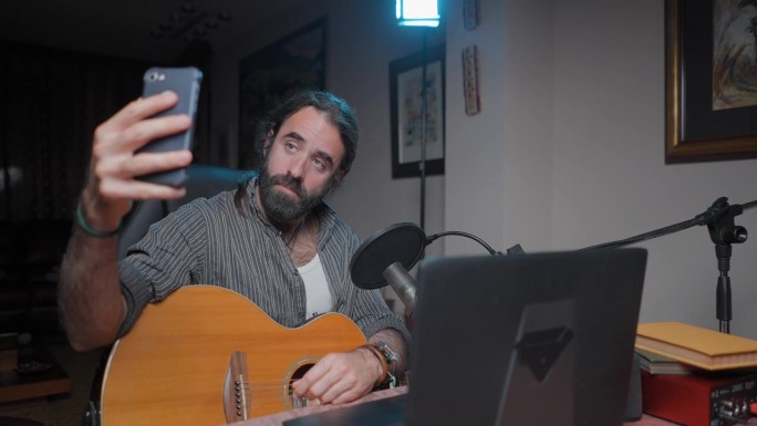 面带微笑的网红音乐家在他的家庭工作室发短信和自拍