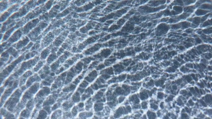 室外游泳池的水波，阳光穿过水面的慢动作场景