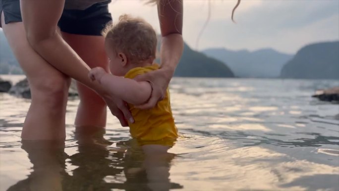 宝宝在湖边玩水，妈妈抱着她