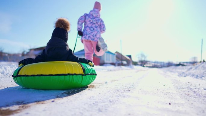 快乐的孩子们在寒假里玩冬季滑冰圈。两个孩子在雪地里玩耍。健康的生活方式。