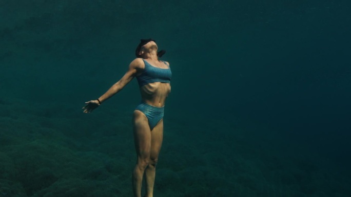 这是一段可循环播放的无缝画面，记录了这名女子在水下游泳，慢慢地接近水面