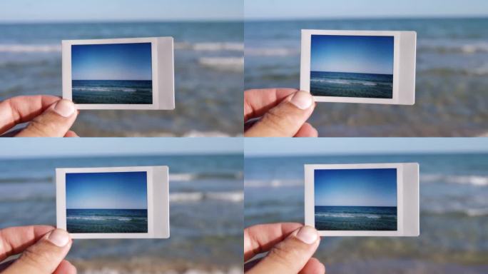 一个人手里拿着一张大海的即时照片，背景是大海。