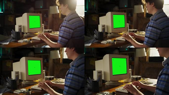 放大镜头的白人男性工程专业学生写论文的旧电脑与绿屏铬在复古车库展示。九十年代科技大学的工程设计