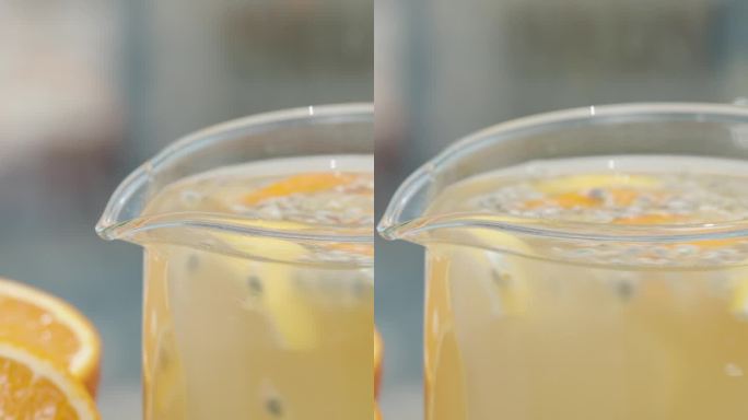 垂直视频。水罐里有柠檬水，桌上有柠檬和橙子片，还有百香果。滑块/