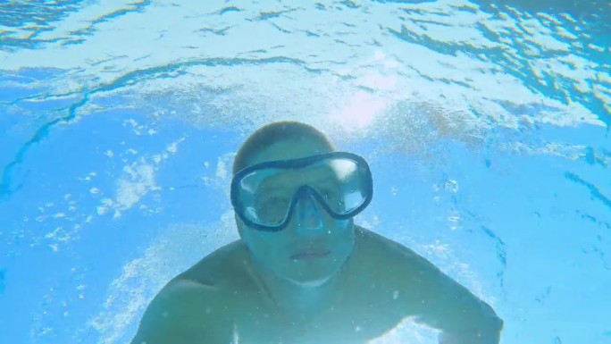 一名男子正在拍摄自己在绿松石海中一艘游艇下潜水的过程