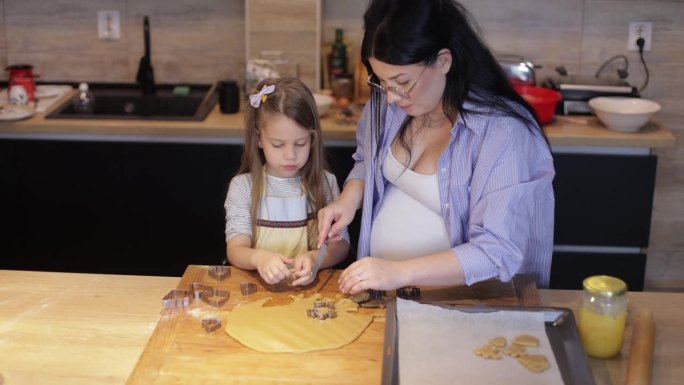 幸福有爱的一家人在一起准备面包房。母亲和女儿在厨房里做饼干，玩得很开心。