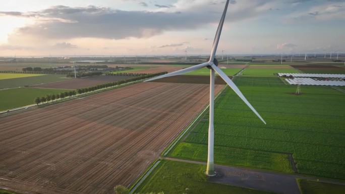 大型旋转风力涡轮机的航拍画面，背景是光电系统(太阳能板)。可再生能源发电，风力发电场和太阳能发电站。