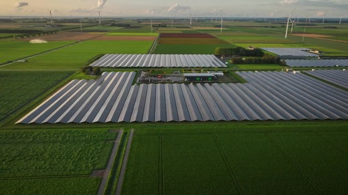 利用光电系统(太阳能板)和风力涡轮机以及农田的可再生能源发电的航拍画面。太阳能板与灌溉与水炮的背景。