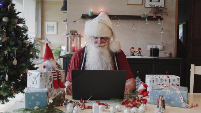 圣诞老人在家里用笔记本电脑工作