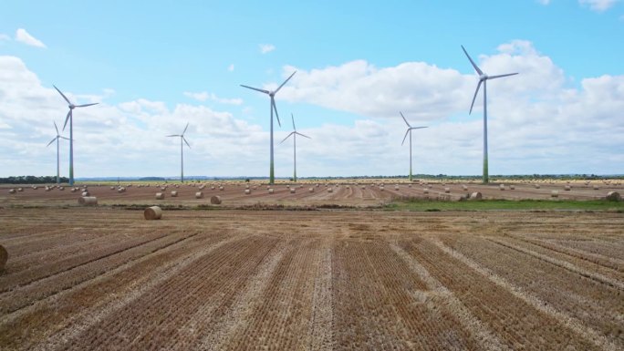 航拍画面显示，在林肯郡农民最近收获的田地里，风力涡轮机运转的宁静之美，金色的干草捆点缀着前景。