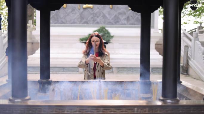 一名亚洲女子在寺庙拜佛祈福