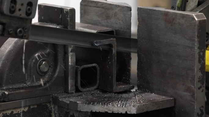 自动带锯机运行，用液体冷却液切割金属轴。用于材料制备的精密切割金属。