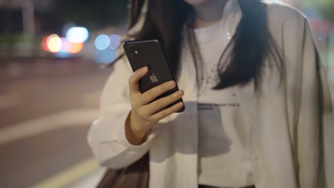 夜晚女孩边走路边玩手机