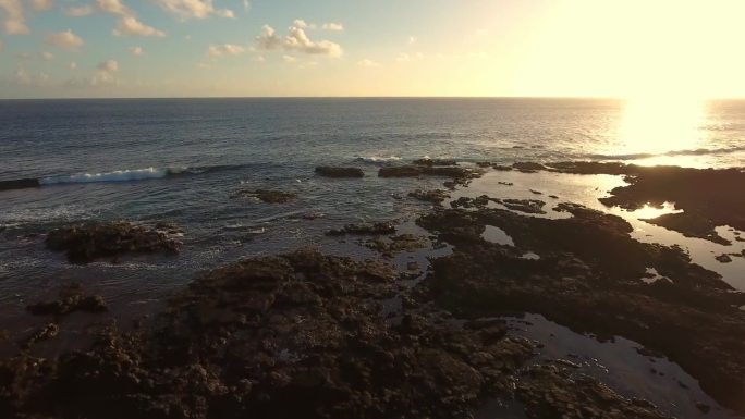 航拍夕阳下的海边礁石海浪天际线