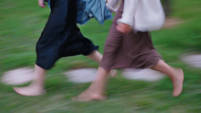 两个女生光着脚在草地上奔跑