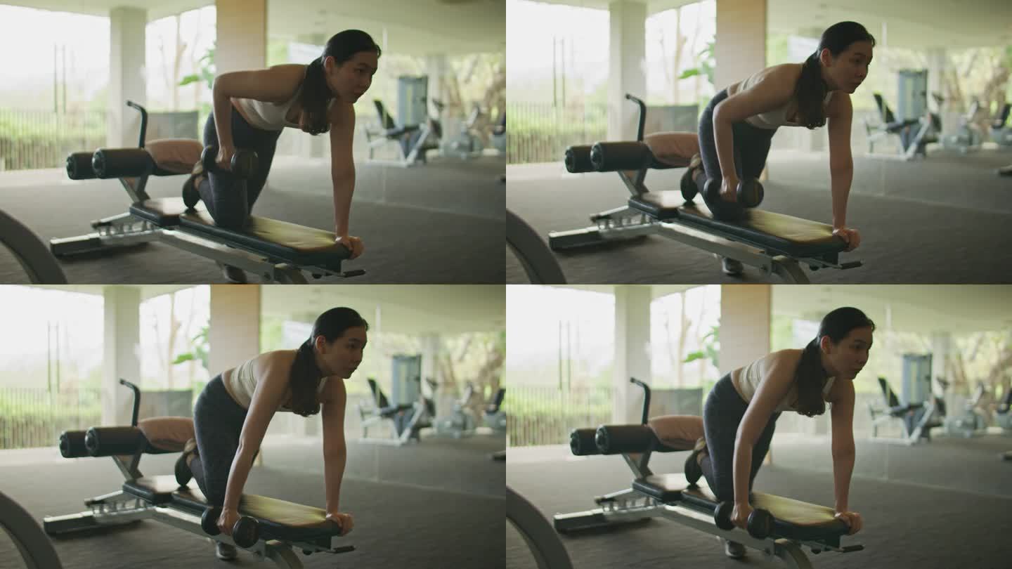 亚洲妇女在健身房锻炼时使用哑铃