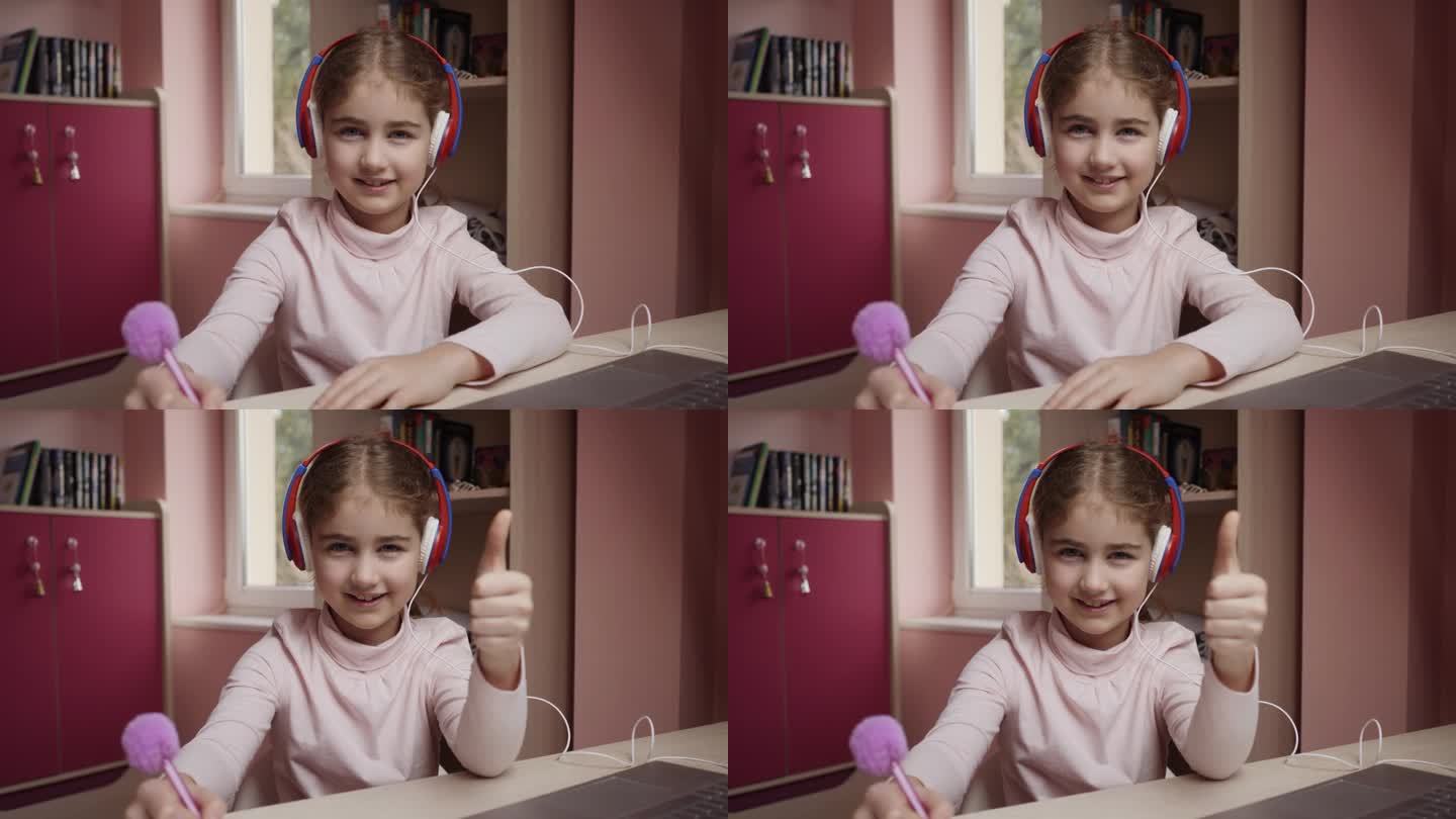 远程学习女生用笔记本电脑在线学习竖起大拇指。戴耳机远程学习的学生表示赞同。白人女孩戴耳机学习在线课程