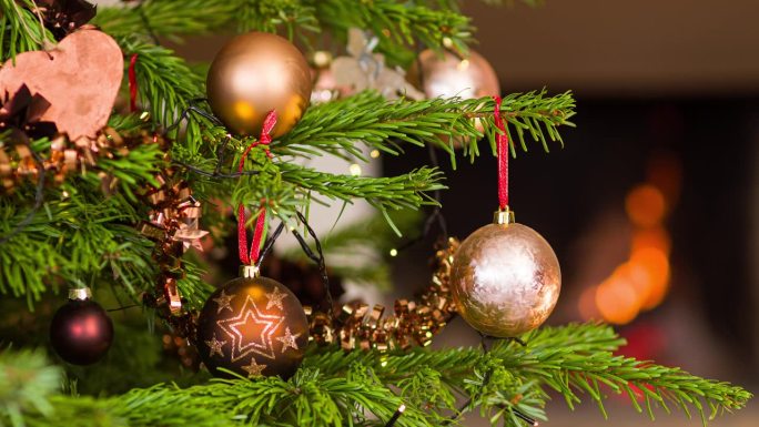 在壁炉旁用一个金色的装饰球装饰圣诞树