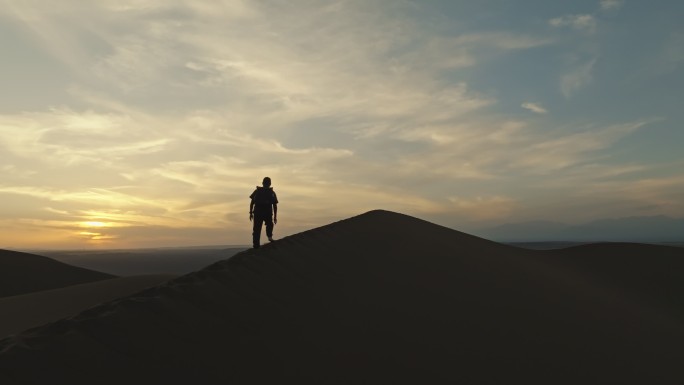 库木塔格沙漠上夕阳晚霞中徒步的人爬沙山