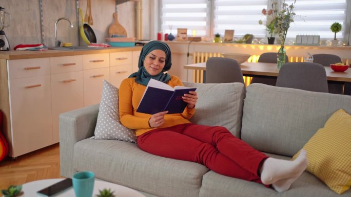 躺在沙发上看书的穆斯林妇女
