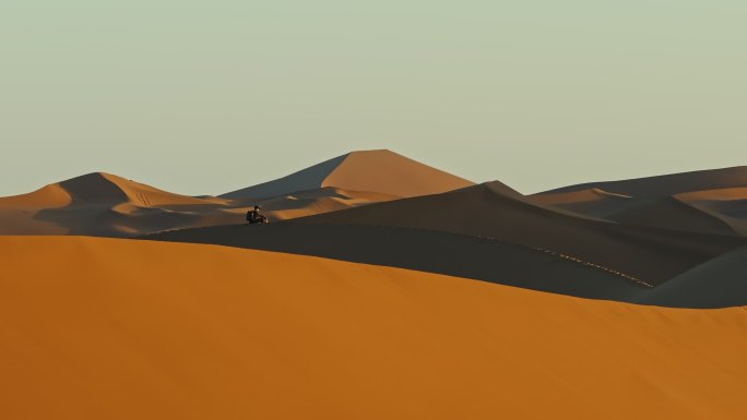 库木塔格沙漠上坐着看夕阳看日落的人
