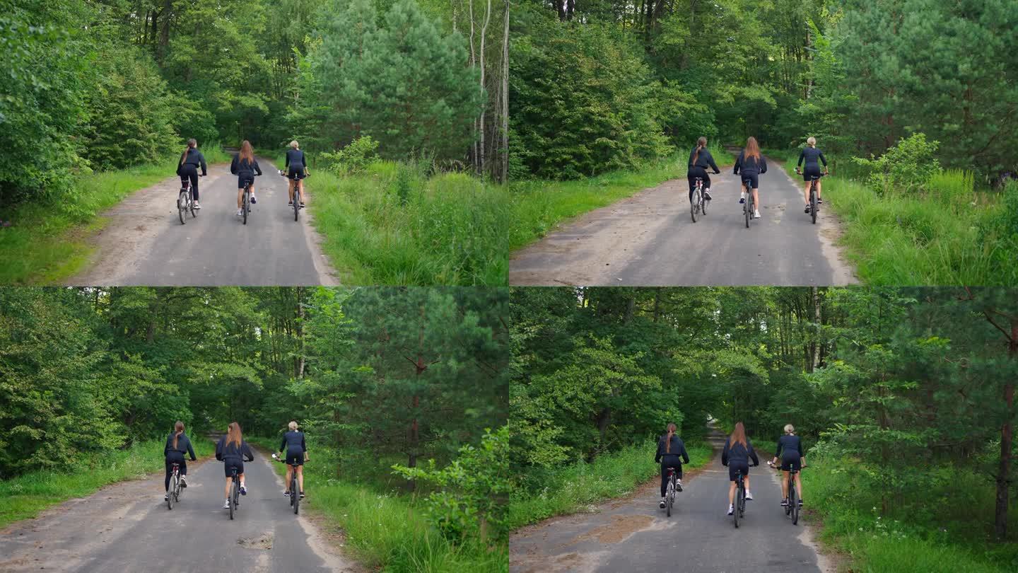 享受夏日周末，三个女人在大自然中骑自行车，在阳光明媚的日子里骑在森林里