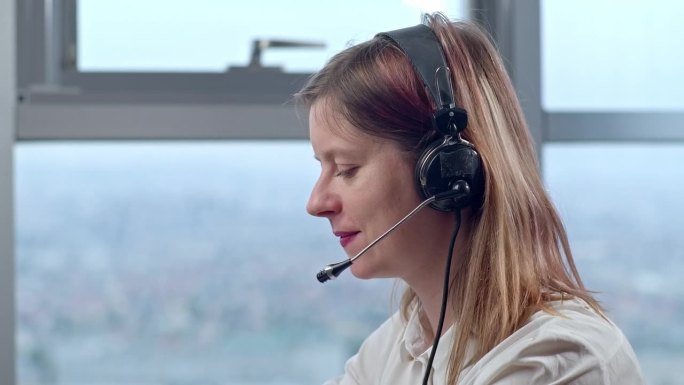一名妇女在电话会议上戴着耳机，呼叫中心的话务员正在与客户交谈