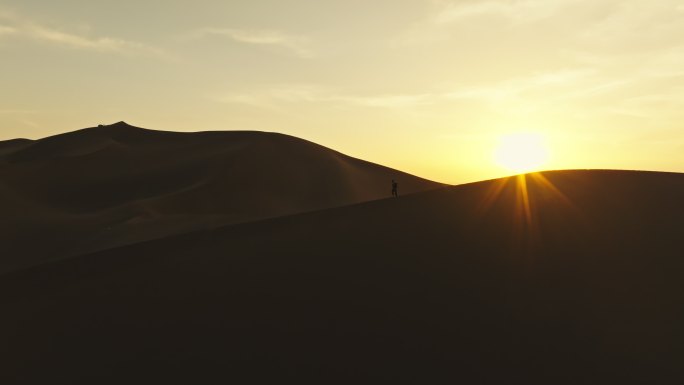 库木塔格沙漠上夕阳晚霞中徒步的人爬沙山