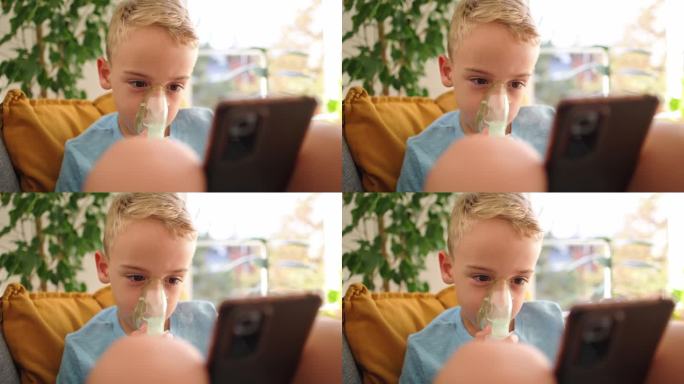 患有哮喘的高加索男孩，在治疗期间，一边使用雾化口罩，一边坐在沙发上用手机看卡通片