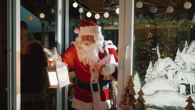 圣诞老人提着礼品盒和灯笼走进屋子，来到圣诞树前留下圣诞礼物的镜头序列