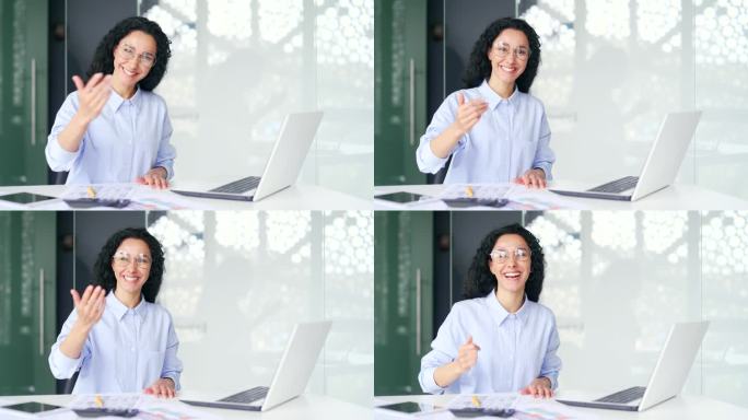 年轻的女员工要求加入她，坐在办公室的笔记本电脑前，用邀请的手势招手。