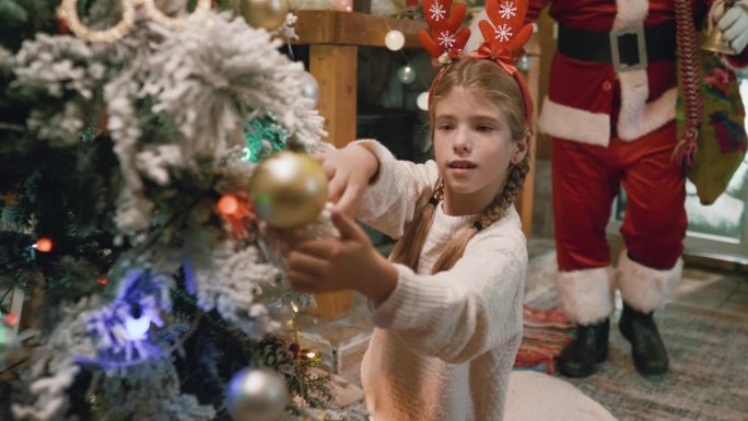 圣诞老人悄悄地溜进了房子，给了一个在新年前夜装饰圣诞树的小女孩一个惊喜。圣诞节的时间。