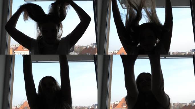 慢动作剪影女孩在窗口玩，她的头发上下摆动