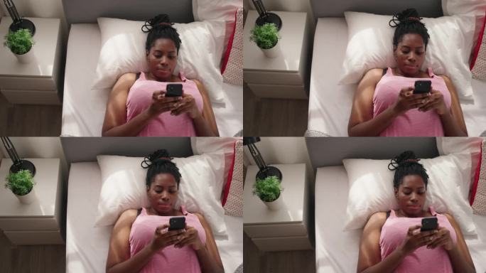 黑人妇女在床上看手机