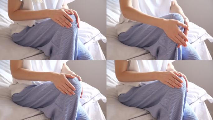 一名穿着睡衣的妇女在清早起床后按摩她疼痛的膝盖