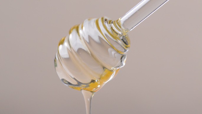 蜂蜜流下缓慢流入 透明液体搅拌棒流下