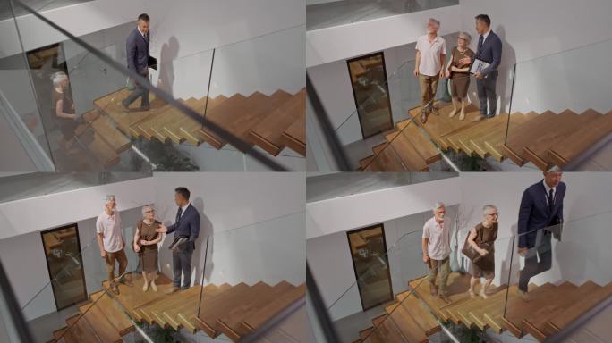 TS房地产经纪人向一对站在楼梯上的夫妇展示房子