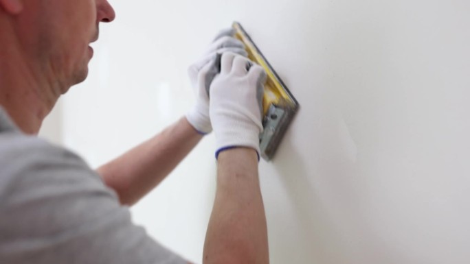 承包商刮掉新房间墙壁不平整的腻子涂层