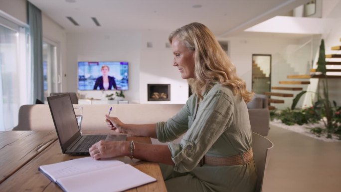 一位中年妇女在餐厅用笔记本电脑开视频会议