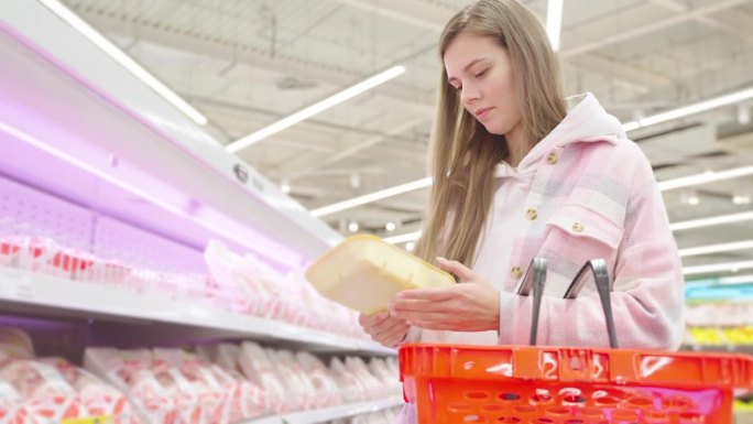 一名妇女在超市买塑料托盘装的鸡肉、猪肉或牛肉。