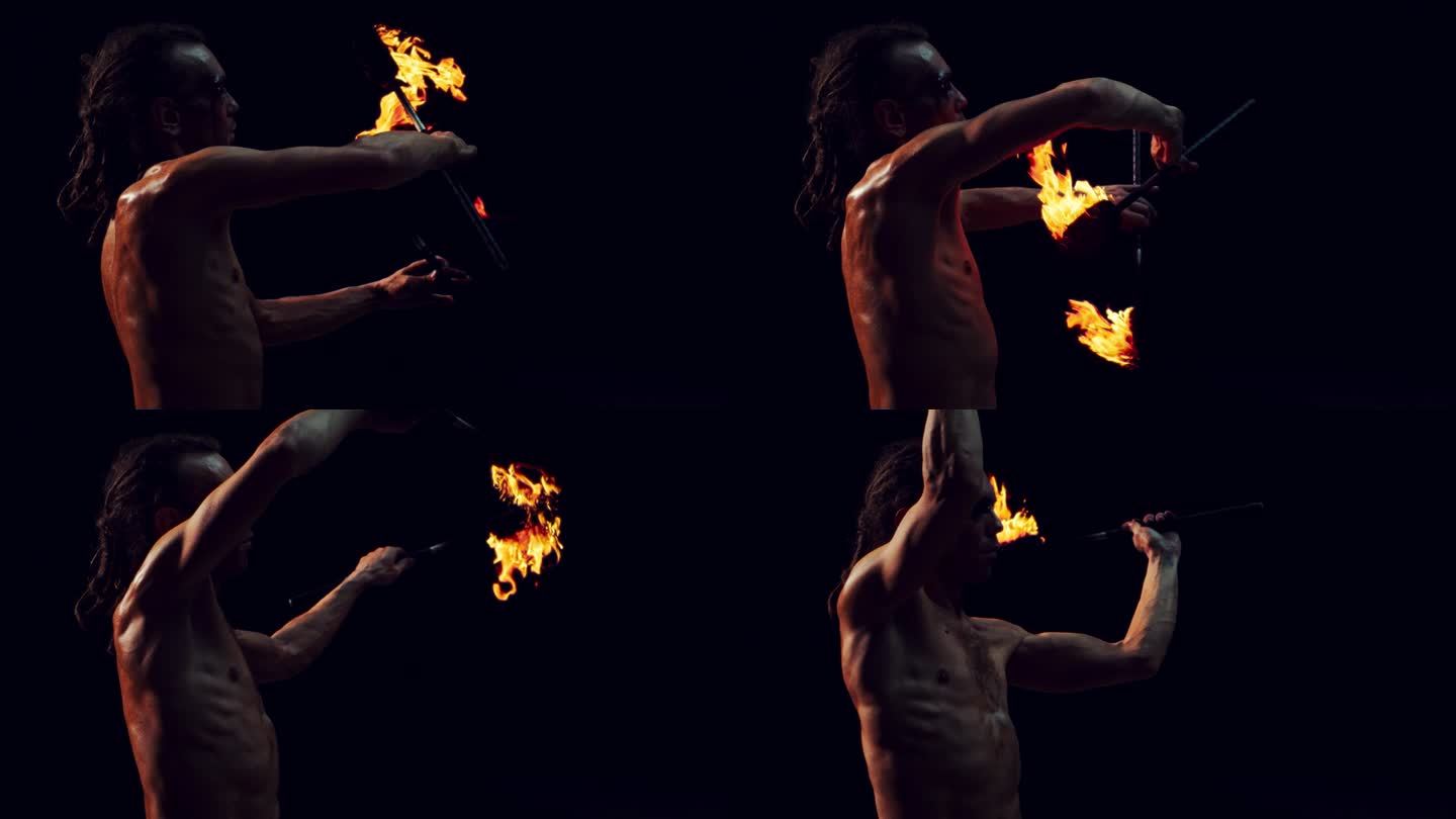 一个在黑暗的工作室里玩弄两个火把的火焰艺术家的肖像。在灯光节或嘉年华的舞台上，一个火焰表演者表演的超