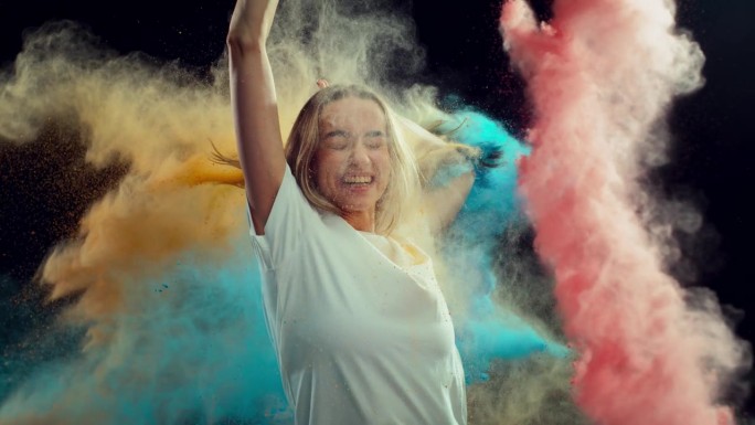 一个美丽快乐的女孩笑着庆祝胡里节的肖像。年轻女性被彩色粉末涂料覆盖。超级慢动作镜头与速度斜坡效果