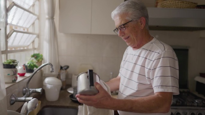 幸福老人在厨房水槽边烘干盘子的真实家庭场景，拥抱家庭生活的仪式