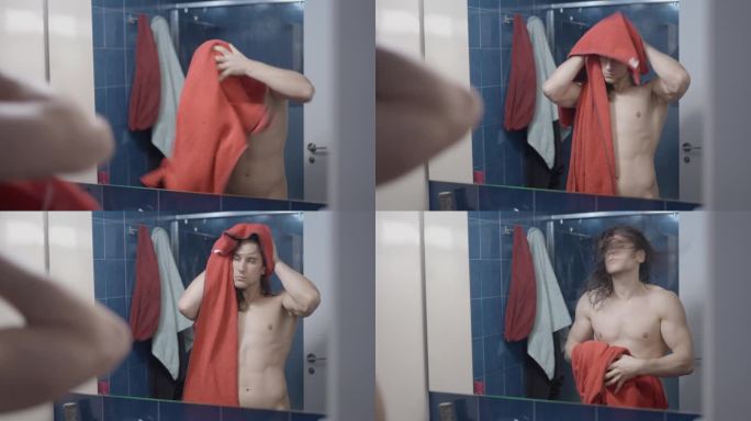 年轻的都市美男淋浴后用红毛巾在浴室镜子前擦干头发-中景
