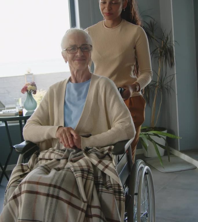 协助在世护士推着坐轮椅的老年妇女穿过客厅