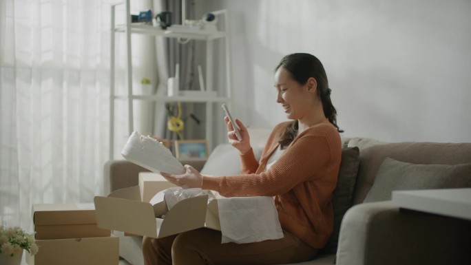 一名女子用智能手机打开网购后的包装盒